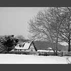 black and white photo of thatched cottage in snow